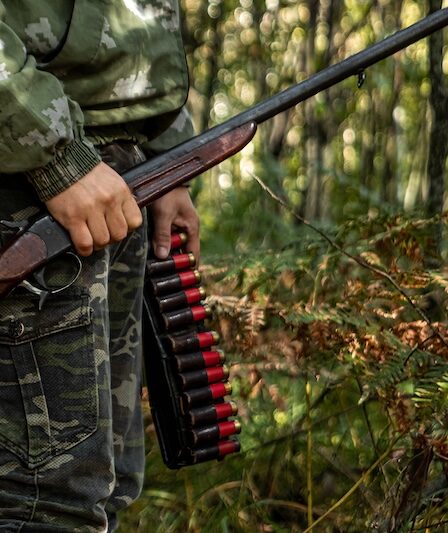 Man med gevär i skogen